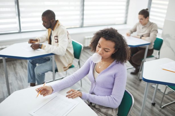 Grupo diverso de estudantes realiza uma prova em uma sala de aula iluminada.